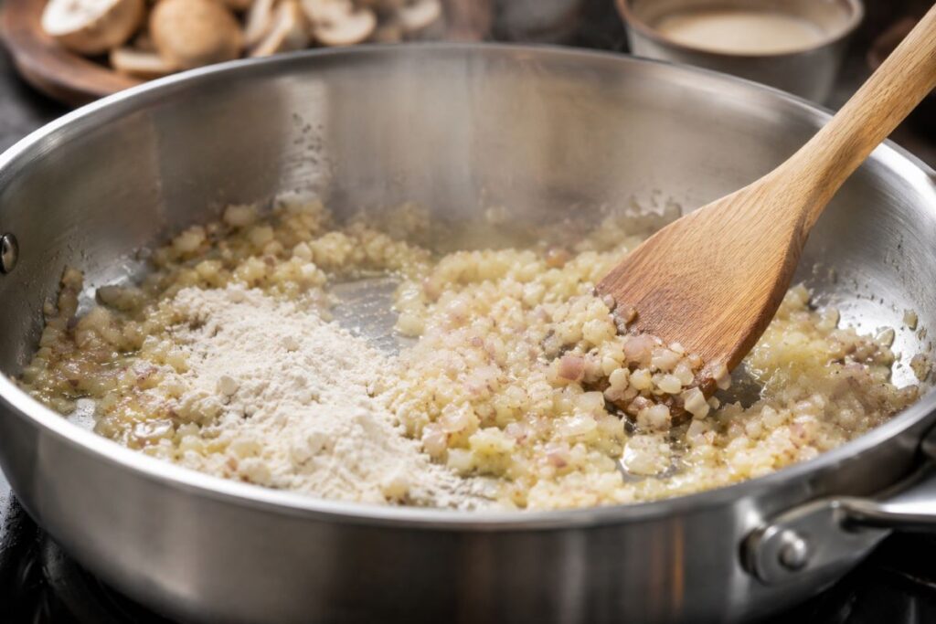 Flour added to sauteed onions in a skillet
