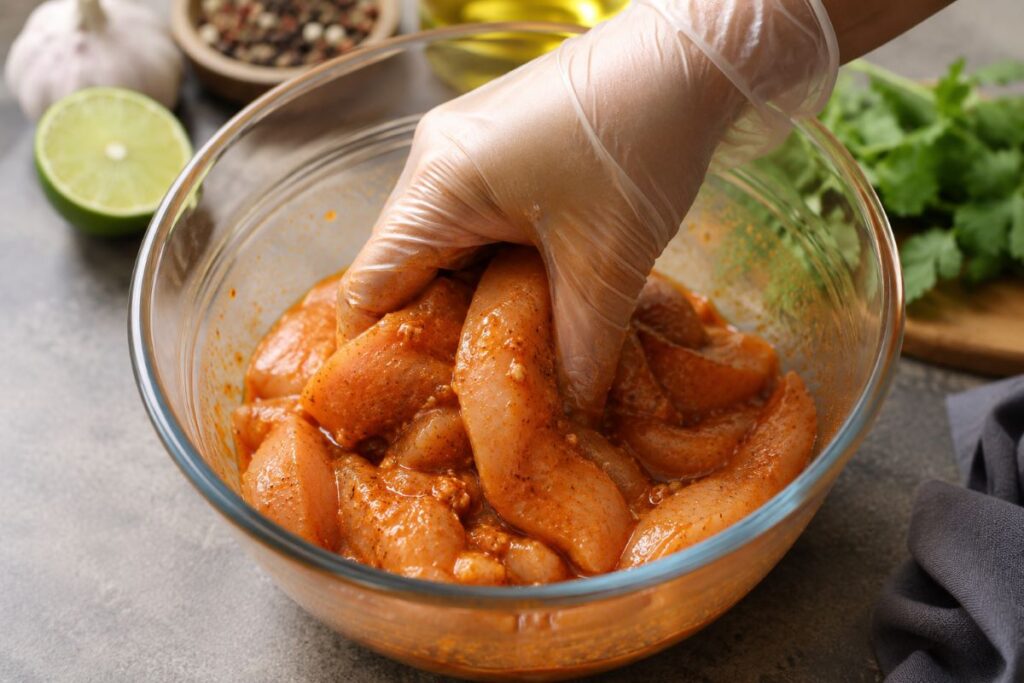 Marinated Chicken strips for fajitas being tossed in a glass bowl